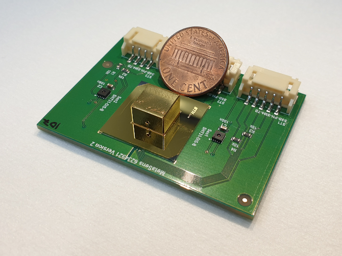 The miniature all-metamaterial optical gas sensor (golden capsule) next to a one-cent coin
